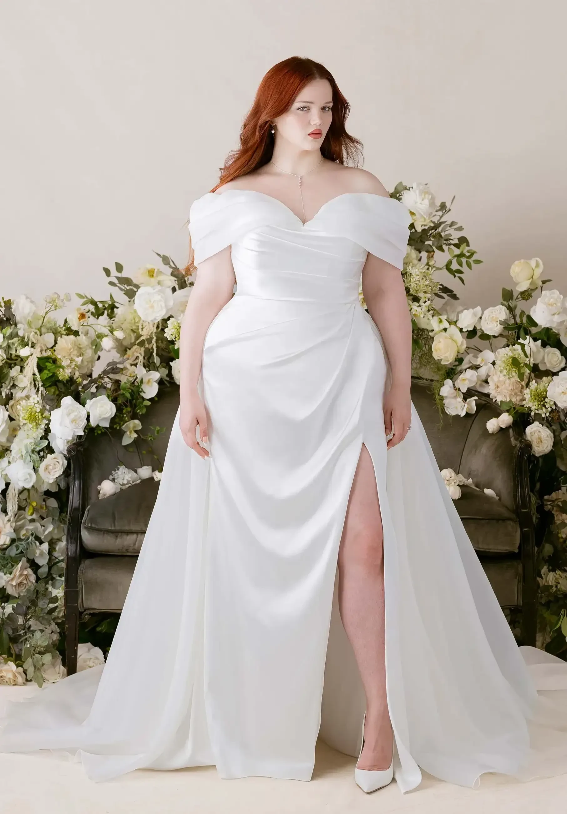 model is wearing an off the shoulder plus size bridal gown