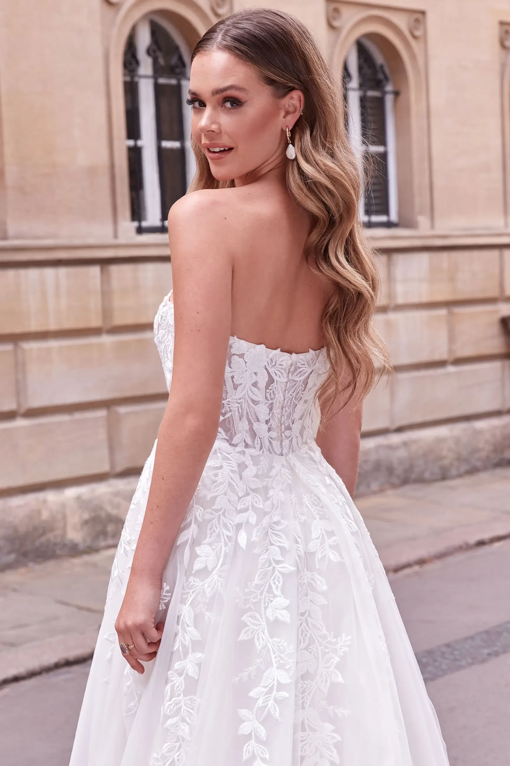 model is wearing a strapless wedding dress by justin alexander