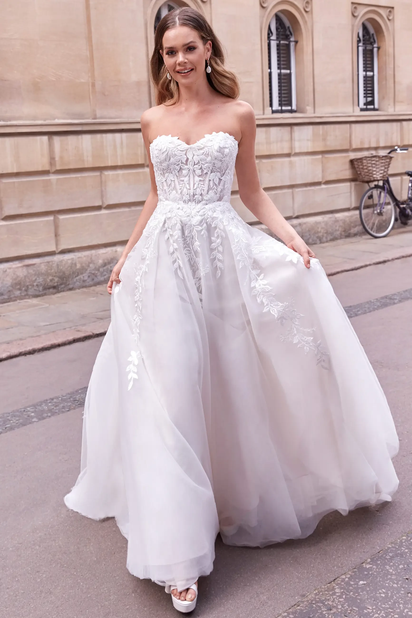 model is wearing a strapless wedding dress by justin alexander