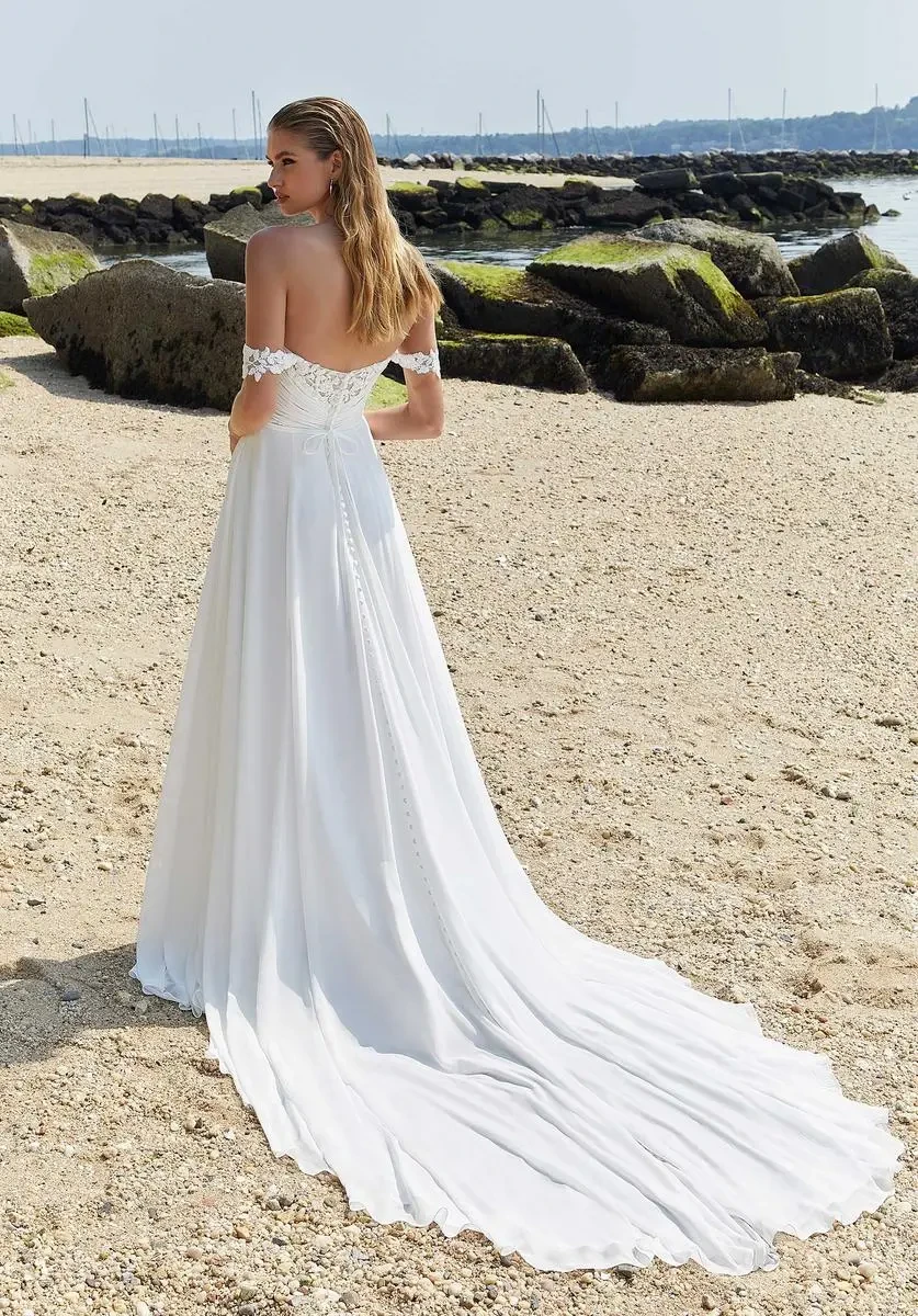model is wearing an a-line bridal gown with off the shoulder short sleeves