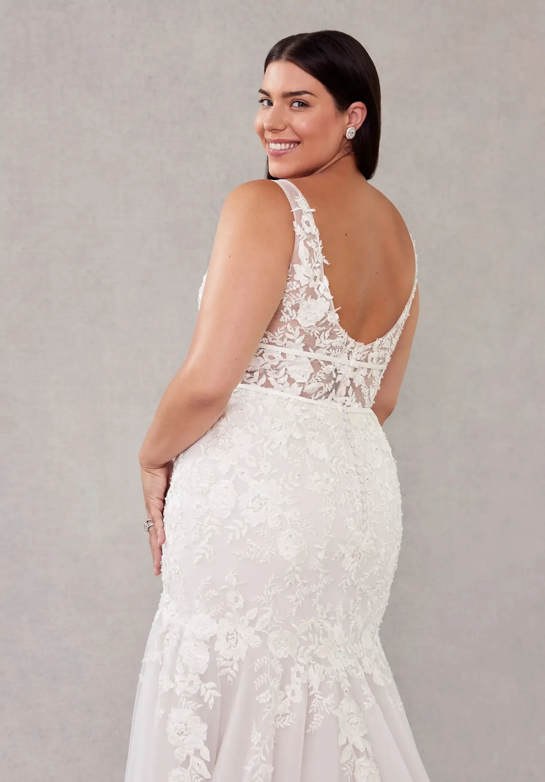 Model is wearing a mermaid plus size wedding dress with soft tulle and crystal beaded floral lace