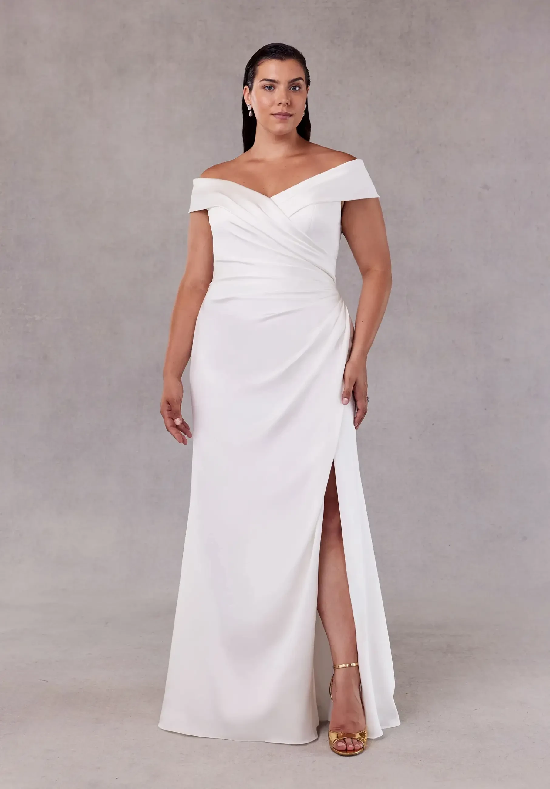 model is wearing an off the shoulder sheath plus size bridal gown