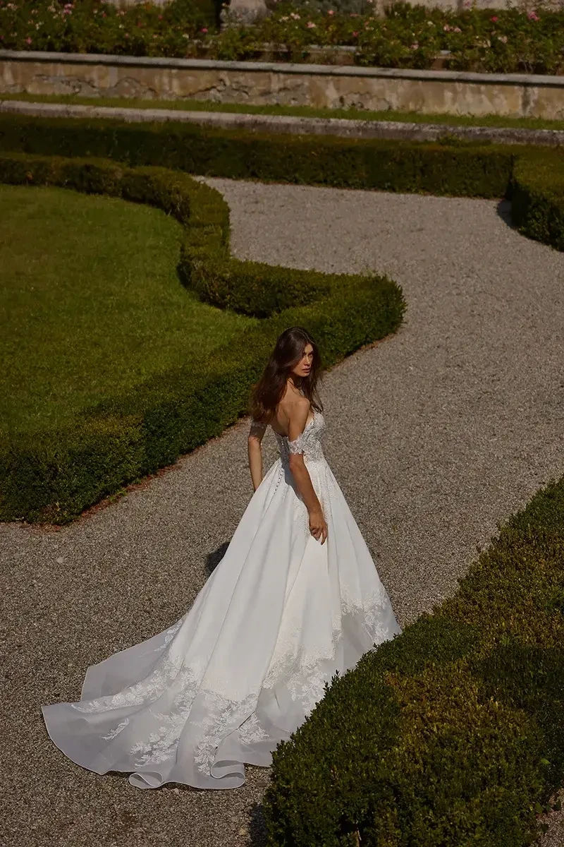 model is wearing an off the shoulder a-line wedding gown