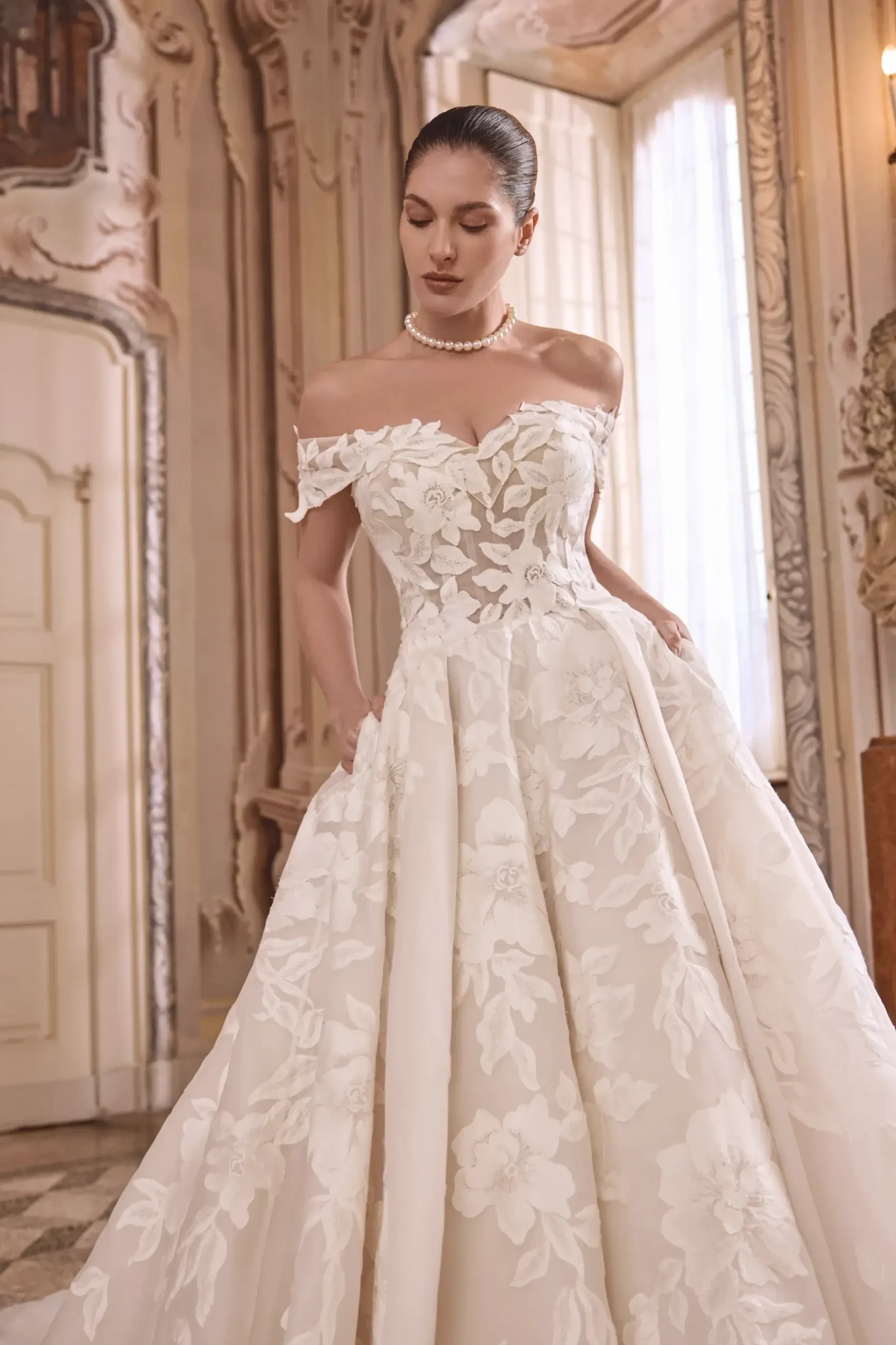 model is wearing an off the shoulder ball gown wedding dress