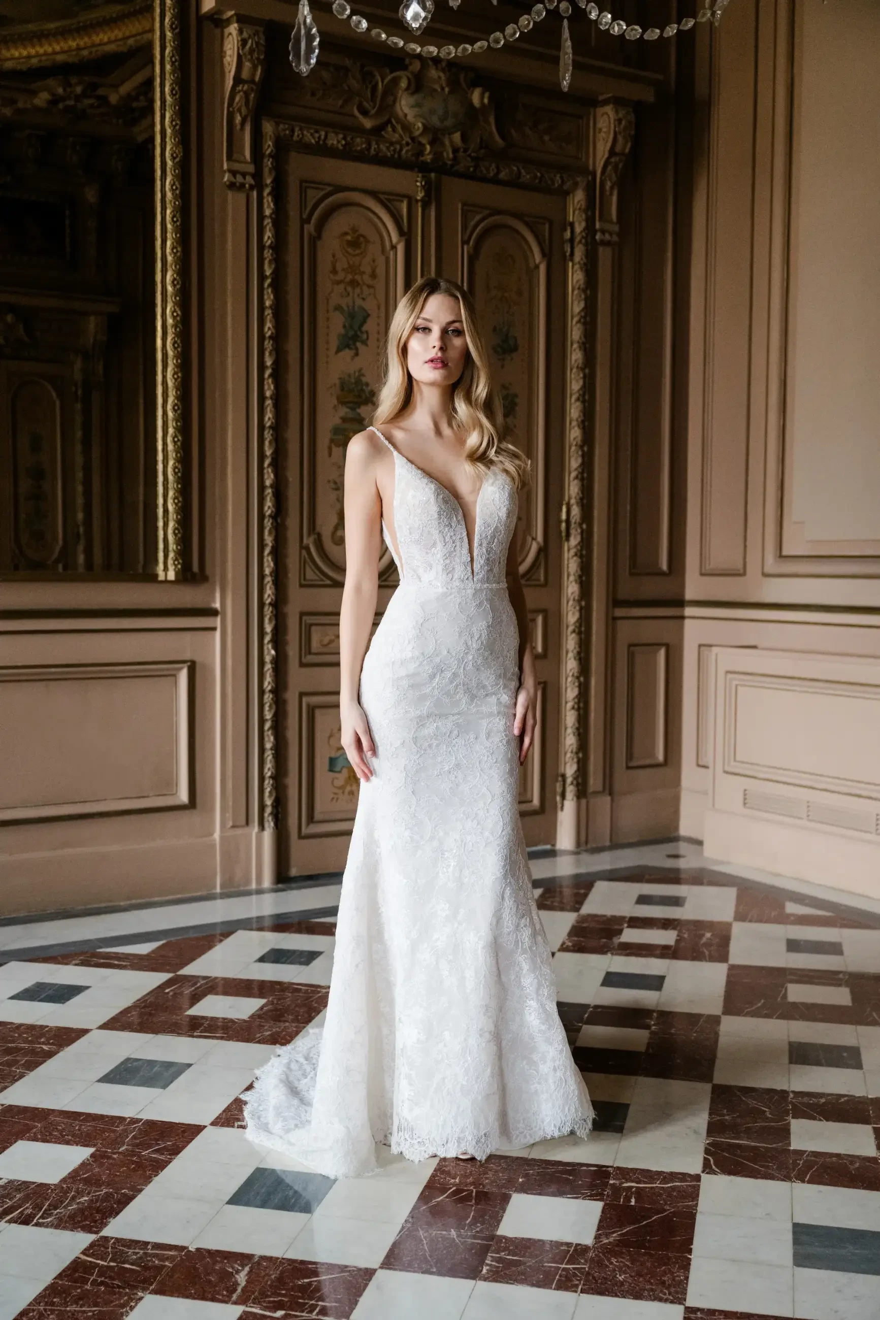 model is wearing a sleeveless sheath open back wedding gown