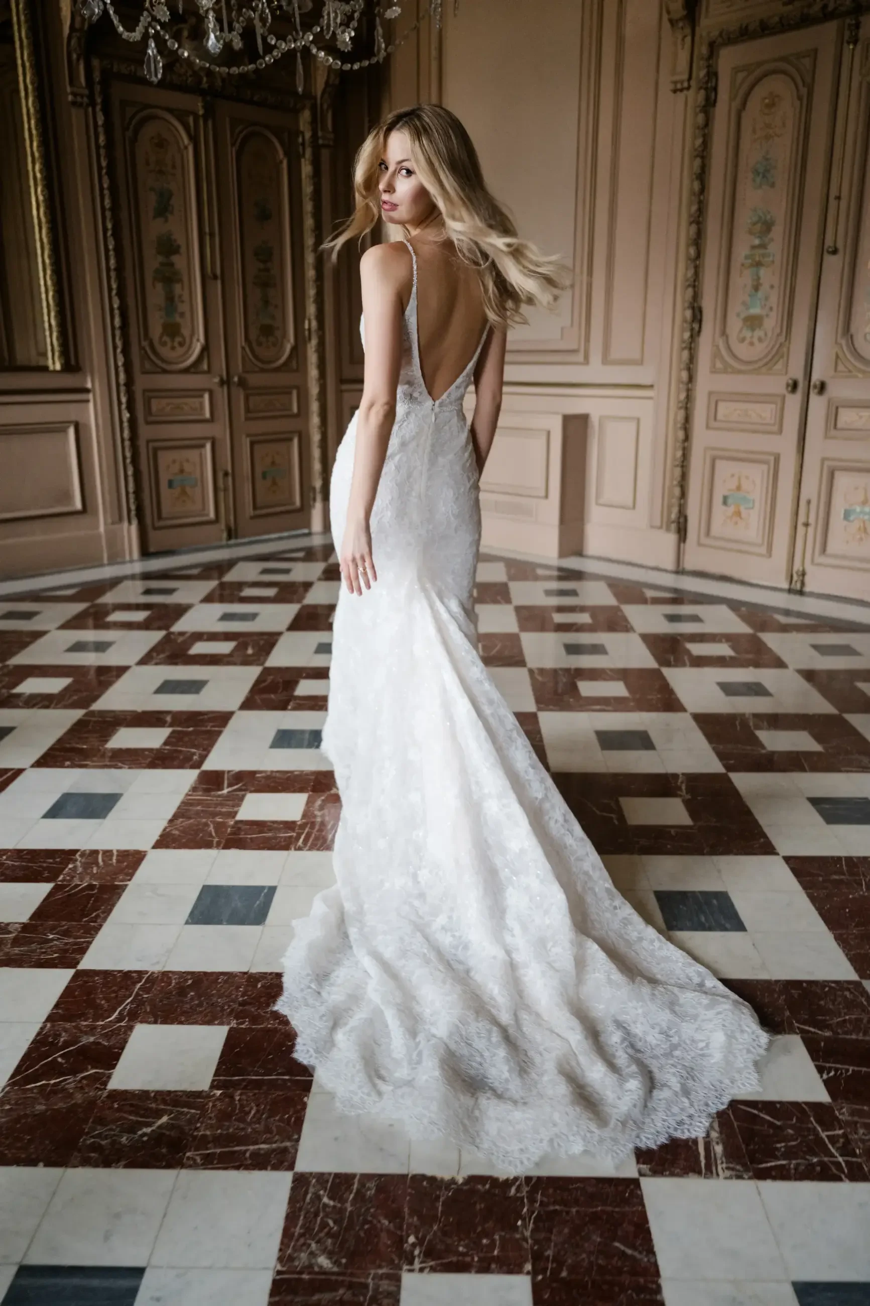 model is wearing a sleeveless sheath open back wedding gown
