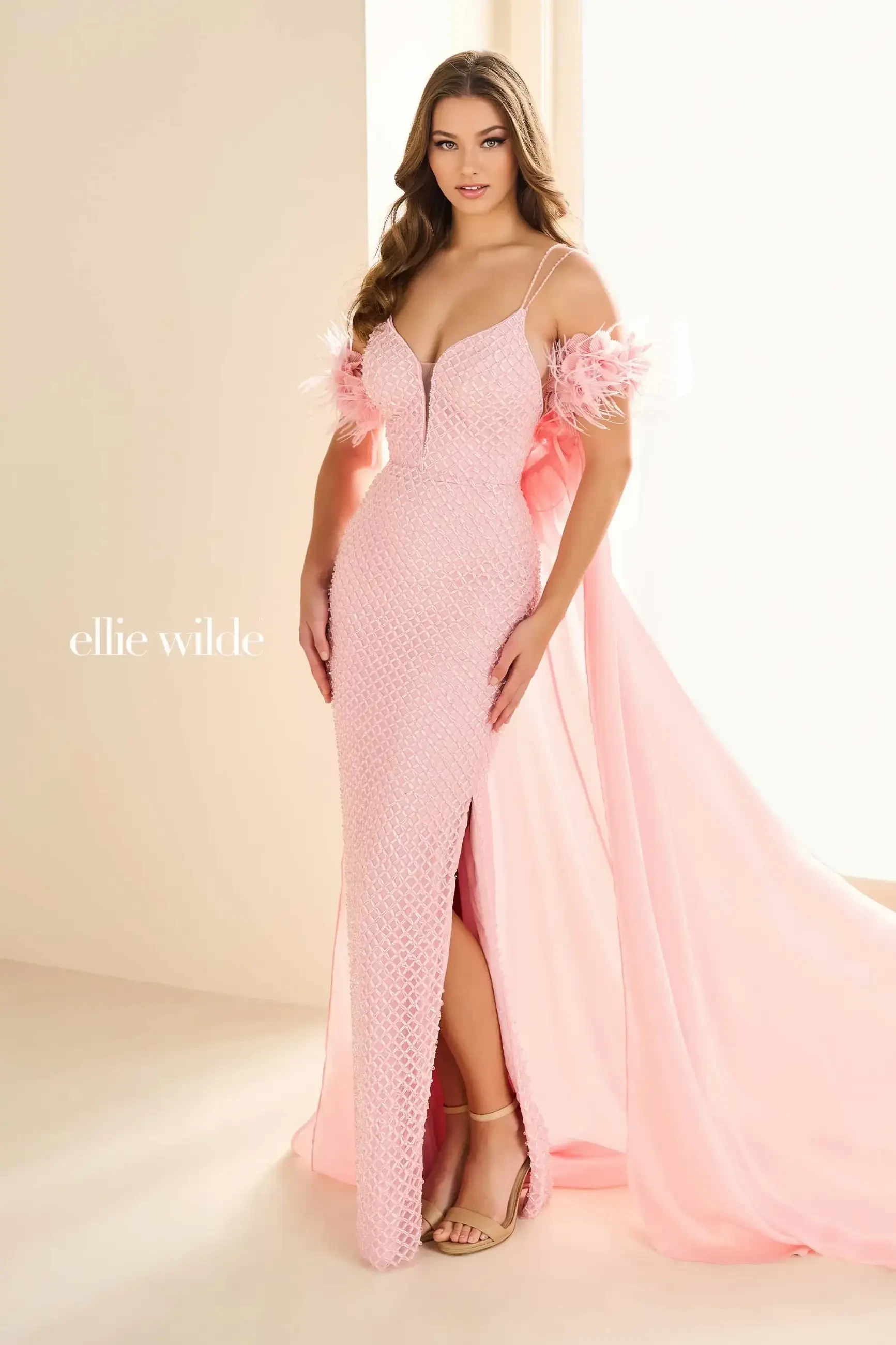 model is wearing a light pink off the shoulder prom dress with feather accents